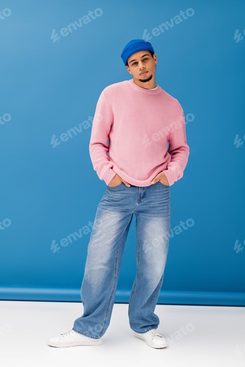 Preview: Handsome young man showcases modern fashion in vibrant studio setting with playful background