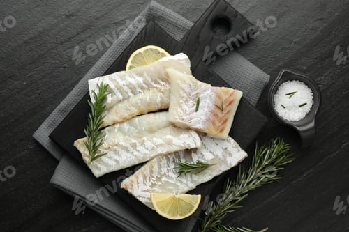 Preview: Fresh raw cod fillets, rosemary, lemon and salt on black table, flat lay