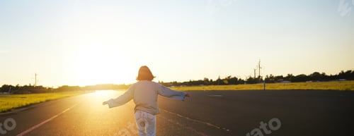Preview: Rear view photo of young girl riding skateboard towards sunlight. Happy young woman on her cruiser