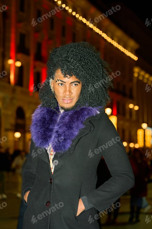Preview: Young man with purple feather boa posing at night in the city