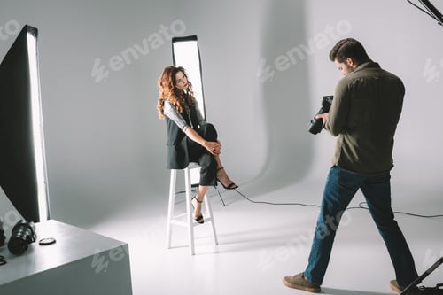 Preview: professional photographer and beautiful model on fashion shoot in photo studio with lighting
