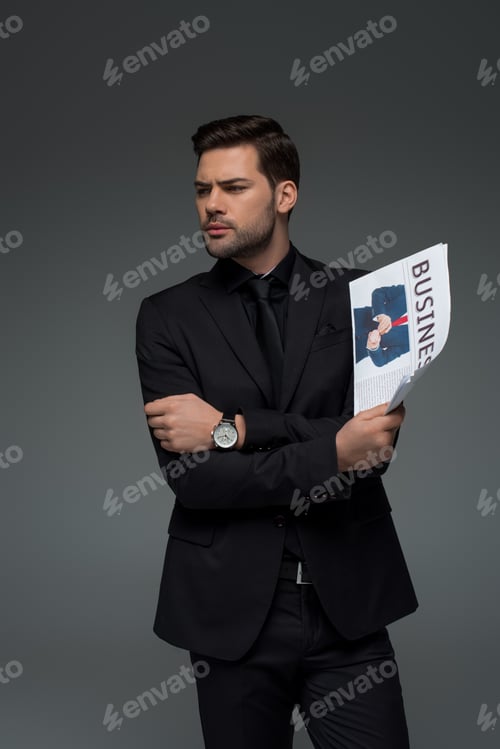 Preview: Young businessman holding newspaper isolated on grey