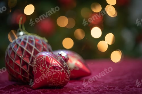 Preview: Elaborate Christmas Ornaments Resting on Table In Front of Lit Tree