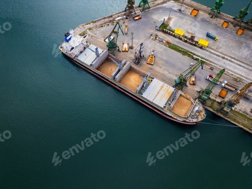 Preview: Aerial view of a cargo ship in a harbor uploading grains in a busy port during daylight hours