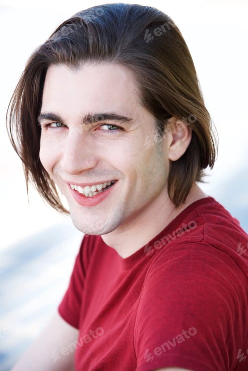Preview: Close up handsome young man with long hair sitting and laughing