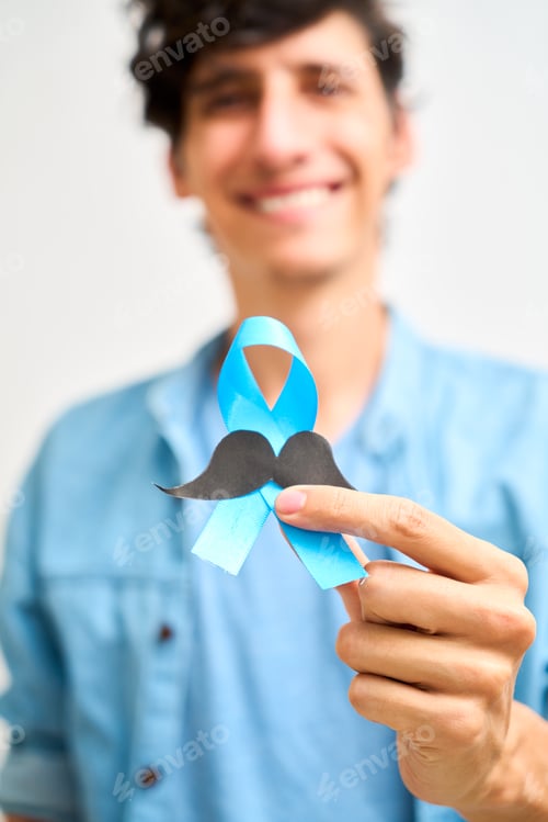 Preview: Cheerful Latin man showing blue ribbon with mustache. Prostate cancer, awareness concept, men Health