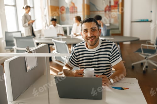 Preview: Smiling Businessman working laptop while sitting in modern office on colleagues background