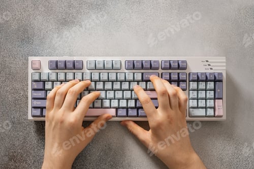 Preview: Teenager hands typing on mechanical keyboard on gray desk.
