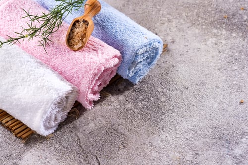 Preview: Color towels with green leaves and a spoon of salt on bamboo mat and stone table, copy space