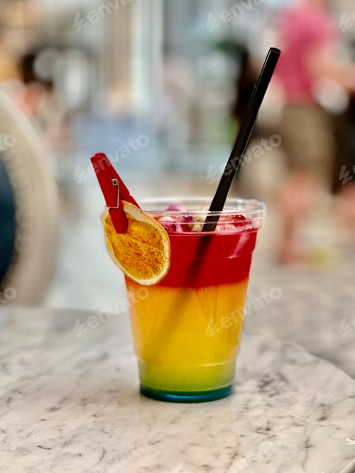 Preview: Closeup of a colorful cocktail in a transparent cup with a black straw