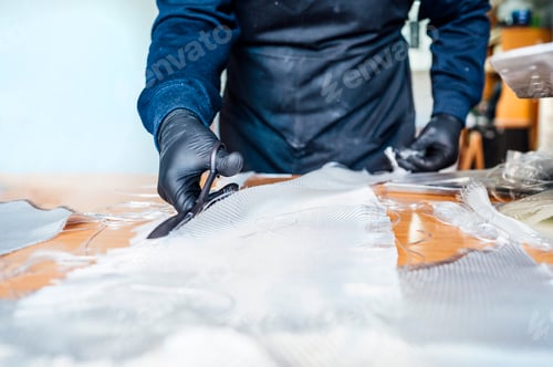 Preview: 62 year old man cutting fiber with scissors in the workshop.