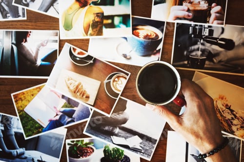 Preview: Hand holding coffee cup with may photograph on the table