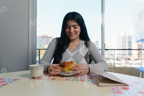 Vista previa: mujer joven en casa feliz con su desayuno