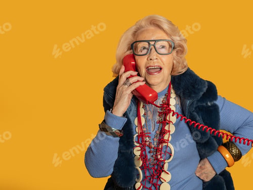 Preview: Stylish senior woman enjoying a phone conversation on vibrant yellow background