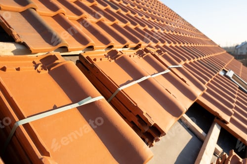 Preview: Stacks of yellow ceramic roofing tiles for covering residential building roof under construction.