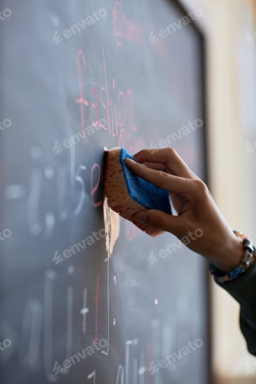 Preview: Focus on hand of young student or teacher wiping blackboard with wet sponge