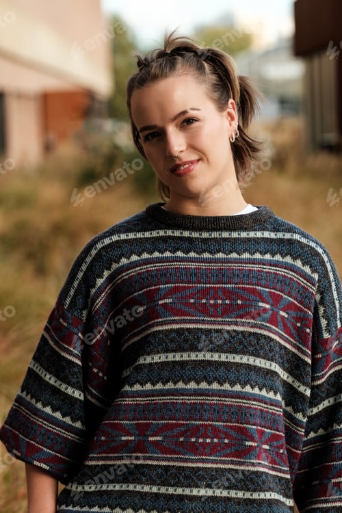 Preview: Young woman wearing a colorful sweater and smiling outdoors