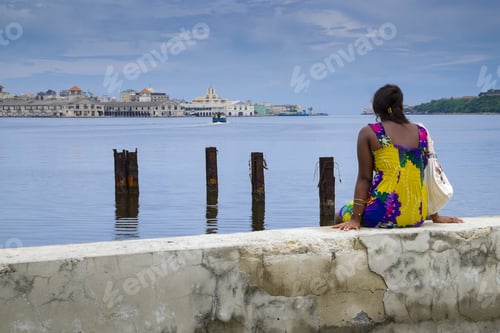Preview: Back view of a woman sitting on a bay in Cuba, Havana