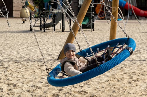 Preview: Boy swings on a spider web swing at a playground