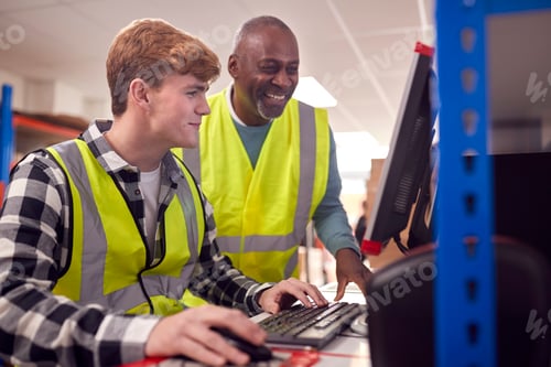 Preview: Male Intern With Supervisor Working In Busy Modern Warehouse On Computer Terminal