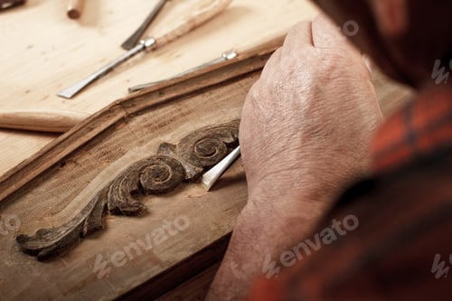 Preview: Senior carpenter working with a hammer, chisel and wood carving tools.