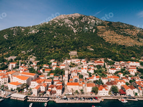 Preview: Bell tower among old houses in Perast against the background of the mountain. Montenegro