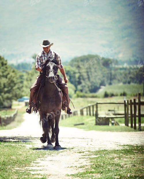 Preview: Yeeha. Shot of a cowboy riding his horse on a country lane.