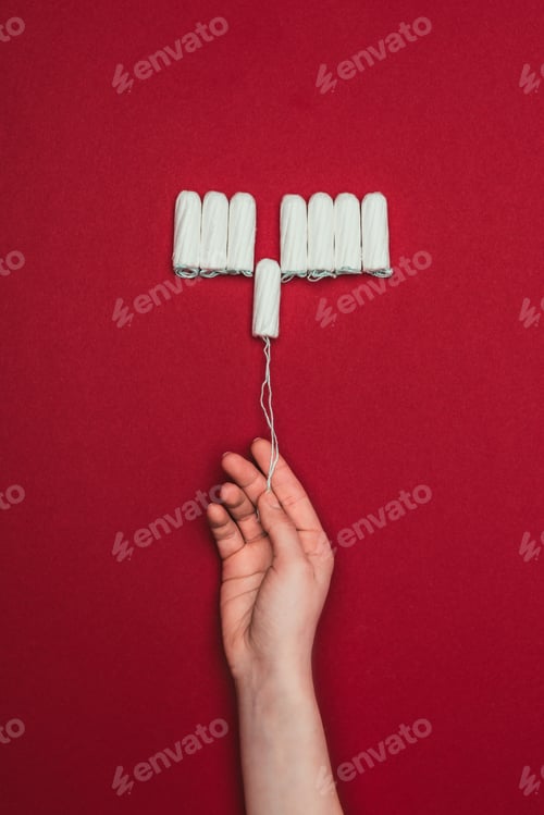 Preview: cropped shot of woman holding tampon in hand isolated on red