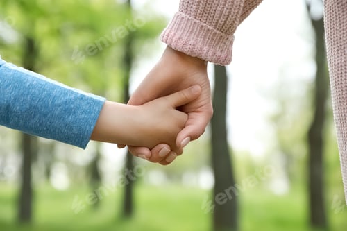 Preview: Little child holding hands with his mother outdoors, closeup. Family time