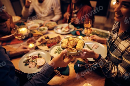 Preview: Close up of couple passing food during Thanksgiving dinner at dining table.