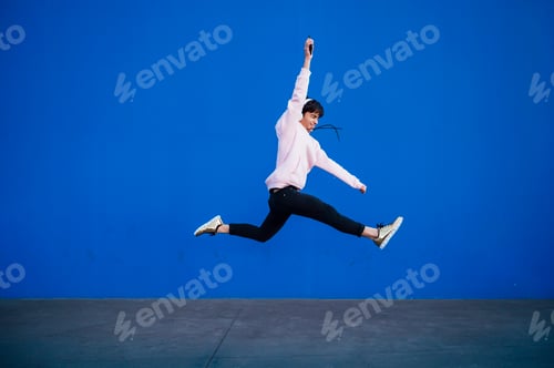 Preview: Teen with headphones and smartphon listening to music jumping
