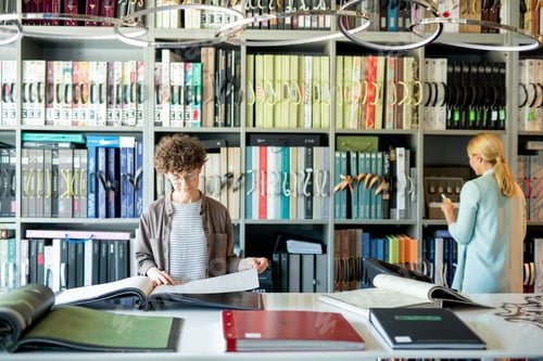 Preview: Young woman looking through catalogue of interior design