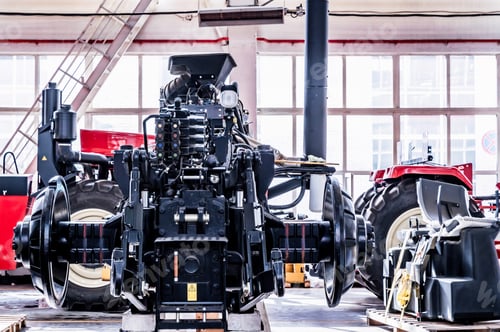 Preview: Big tractor wheels installation at assembly room at industrial plant