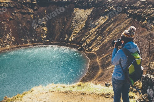 Preview: Back view of woman taking pictures in crater