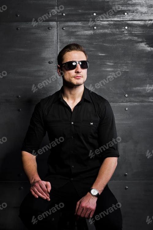 Preview: Studio portrait of stylish man wear on black shirt and glasses against steel wall.
