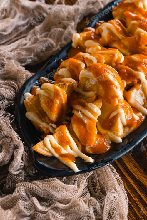Preview: Close up of traditional Spanish Patatas Bravas, baked potatoes with spicy tomato sauce