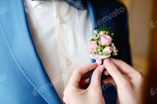 Preview: Groom and bride are wearing a boutonniere indoors