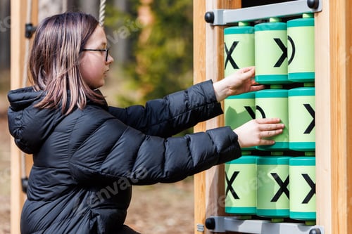 Preview: Girl outdoors on wooden Ecological playground in forest park in spring, playing.