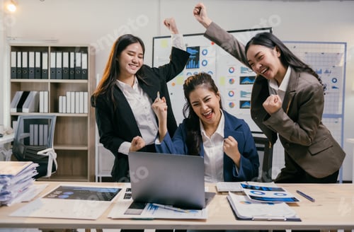 Preview: Three asian businesswomen are cheering and celebrating their success while looking at a laptop in a