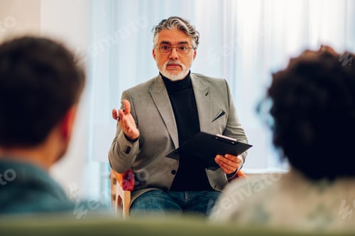 Preview: Senior man psychiatrist talking with his patients during therapy session