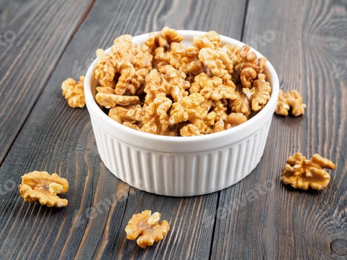 Preview: Side view white bowl with a handful of walnut, circassian nuts on a wooden dark background
