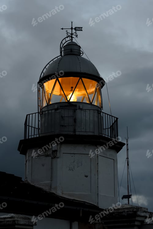 Preview: Shining lighthouse against cloudy sky