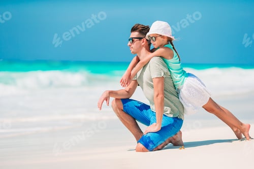 Preview: Happy father and his adorable little daughter at tropical beach walking together