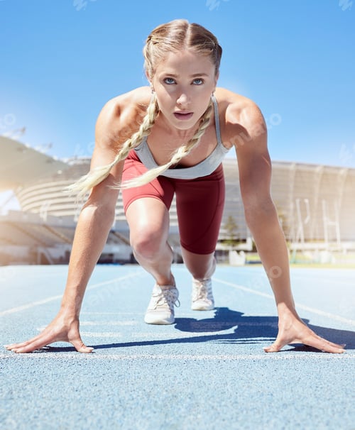Preview: Determined female track runner in starting position. Front view of fit active sportswoman mentally