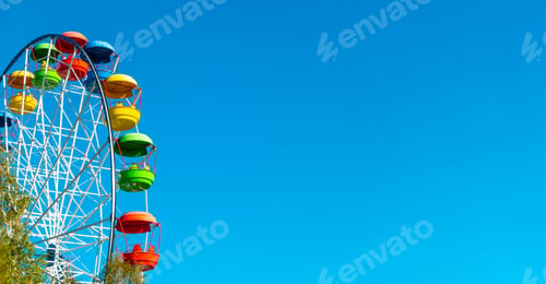 Preview: landscape of an amusement park with the top of a Ferris wheel showing above the tree tops against a