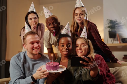 Preview: Cheerful intercultural friends looking at smartphone camera and making selfie