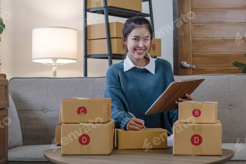 Preview: Portrait young attractive asian female owner startup business work happy with box at home prepare