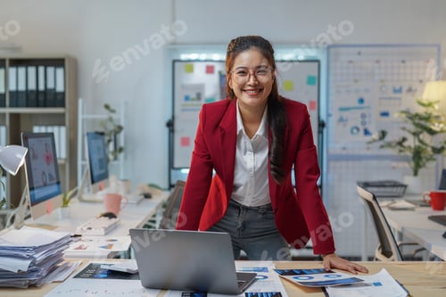 Preview: Young manager working with a laptop and financial documents, standing confidently near a desk in a m
