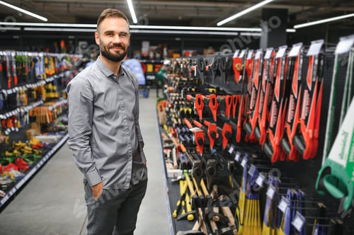 Preview: male builder in a hardware store chooses a tools