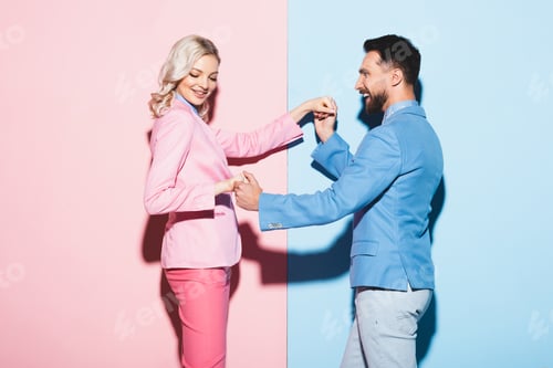 Preview: smiling woman and handsome man holding hands on pink and blue background